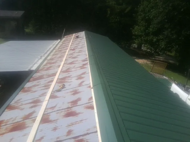 Old rusted panels beside newly installed green metal roofing — Wind Damage Roof Repair by Roofing Brothers in Cherry Valley